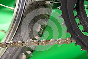 part of bicycle chain, tire and chainset teeth.  green background.