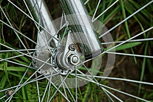 Part of a bicycle with a gray iron  fork and spokes on a wheel