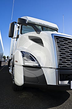 Part of big rig semi truck with grille and headlight on the truck stop