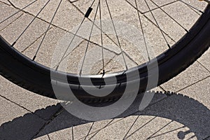 Part of a black bicycle wheel with metal spokes