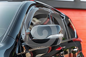 Part of the black modern car. Close-up rearview mirror. Exterior detail