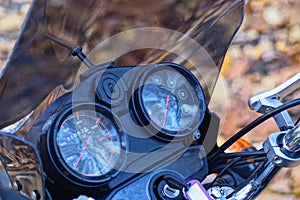 part of a black motorcycle with round speedometers and steering wheel