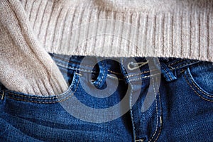 Part of blue jeans and woolen pullover close up. Selective focus