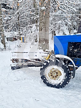 part of a blue tractor with large wheels in a snowy forest.