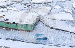 Part of boat and plastic chair on frozen river Danube