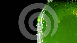 Part of a bottle of cold beer. Drops of condensate flow down the glass. On a black background, the free space of the