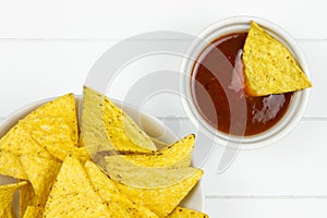 Part of a bowl filled with tortilla chips and dipping