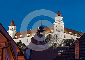 Část bratislavského hradu s kostelní věží v průčelí ve večerních