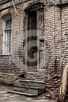 part of a brick wall of an old house with an old peeled wooden door and window