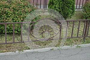 Part of a brown decorative fence with a wrought iron pattern