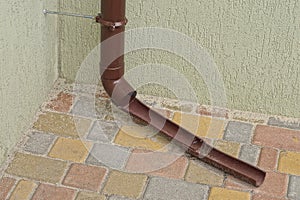Part of a brown plastic drain pipe on a gray wall of a building