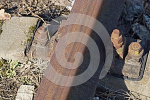 Part of brown steel rails and rusty bolts and nuts on the railroad