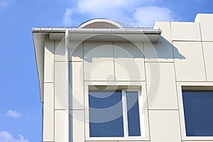 Part of a building wall with window and gutter against the blue sky