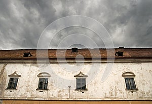 Part of castle Moravsky Krumlov, Czech Republic. Detail of old house with old flaked away facade and dramatic dark clouds above