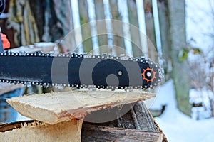 Part of a chainsaw with a black tire and a chain on a wooden board
