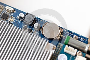 Part of a computer motherboard with capacitors, a battery and a cooling radiator