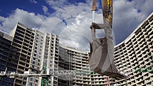 Part of a construction machine excavator or crane with multi-storey building under construction new residential complex on the