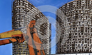 Part of a construction machine with multi-storey building under construction with scaffolding on the background