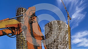 Part of a construction machine with multi-storey building under construction with scaffolding on the background