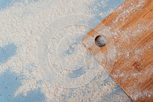 part of a cutting wooden board on a blue background with flour