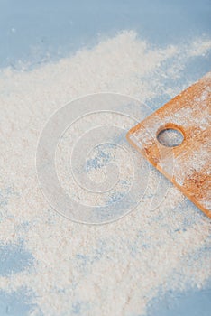 part of a cutting wooden board on a blue background with flour