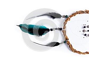 Part of a Dreamcatcher made of willow branche and green, black feathers, placed horizontally on a pure white background
