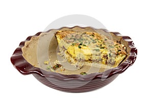 Part of an egg, sausage and green onion quiche in a red ceramic baking dish
