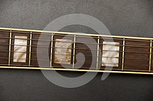 Part of electric guitar on black background. Metal strings. Neck of guitar. Frets of guitar photo