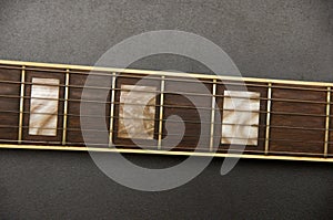 Part of electric guitar on black background. Metal strings. Neck of guitar. Frets of guitar