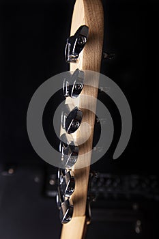 Part of electric guitar headstock against black background.