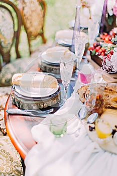 The part of the elegant wedding table setting in the rustic style. The table is decorated by wineglasses, lovely candles