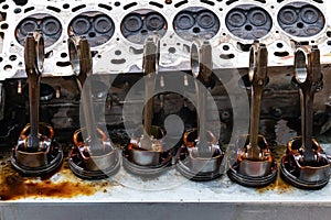 Part of the engine removed from a used car for repairing silver metal and aluminum with six pistons in oil on a workbench in a