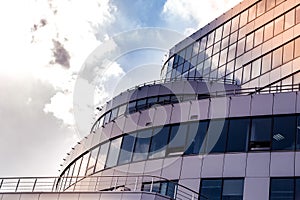 Part of the facade of a building finished with modern materials and the clouds and the sun that reflecting in the windows as a bac