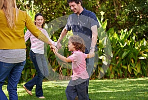 Part of the family circle. a family playing ring-a-rosy together in the garden.