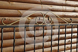 Part of the fence of black metal rods against a wooden brown wall