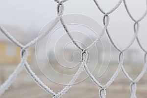 Part of the fence made of metal wire covered with frost