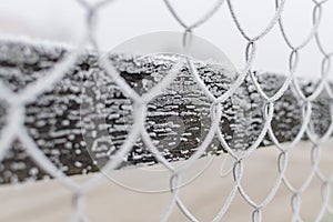 Part of the fence made of metal wire covered with frost