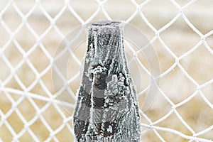 Part of the fence made of metal wire covered with frost