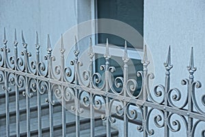 Part of the fence of sharp steel rods against the wall of the house with a window