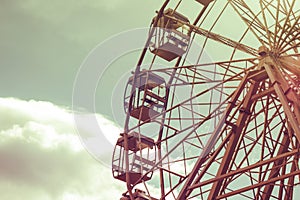 Part of a Ferris wheel against a blue sky with a light