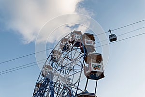 Part of a ferris wheel with colorful vintage cabins on a background of blue sky with clouds. Amusement park in Spain