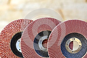 Flap grinding wheels of different grains on wood and metal on a light beige background in unsharp photo