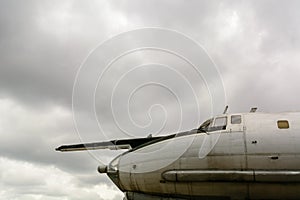 Part of the fuselage of the old military plane with the propeller closeup against the background of an empty and gray