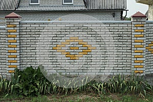 Part of a gray brick wall of a fence