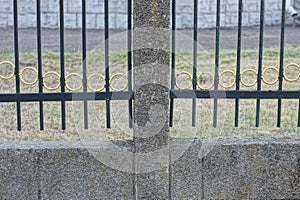 Part of a gray metal fence made of iron bars on a concrete foundation