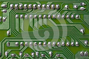 A part of a green printed circuit computer board with tracks. PCB without radio components. Old printed circuit board background