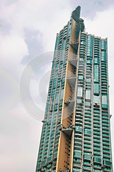 Part of green skyscraper against cloudy sky in bangkok