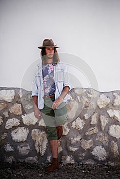 Part of the hipster lifestyle. a trendy young man leaning against the wall of a building outside.