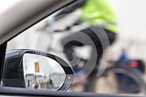 Part inside view of a car, a car mirror and a partial view of a cyclist