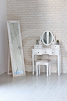 Part interior of bedroom, against wall there is pier glass with an oval mirror and white rectangular mirror